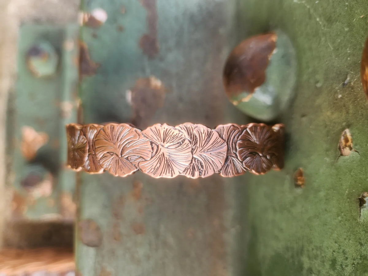 Close-up of overlapping floral pattern on copper cuff bracelet