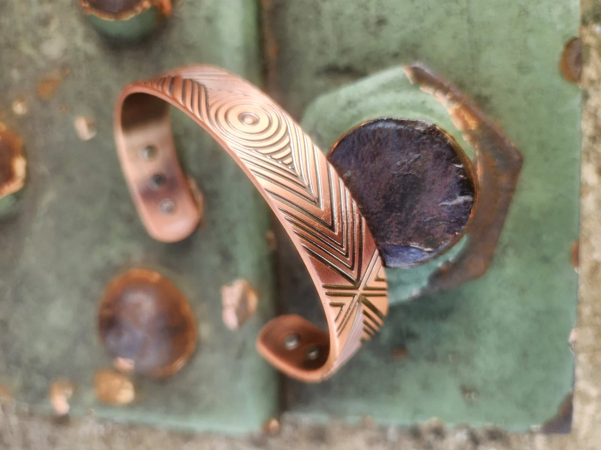 Angled copper cuff bracelet showing geometric pattern and inset magnets