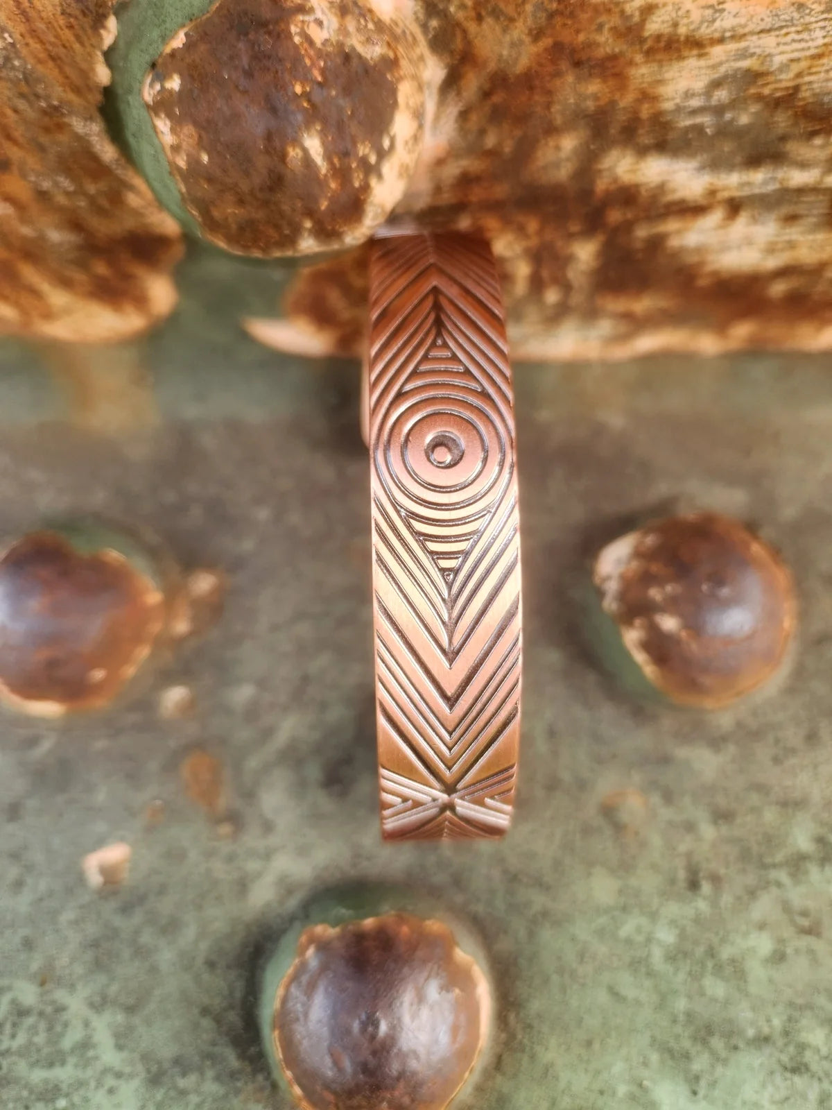 Close-up view of the concentric circle and chevron pattern on copper cuff