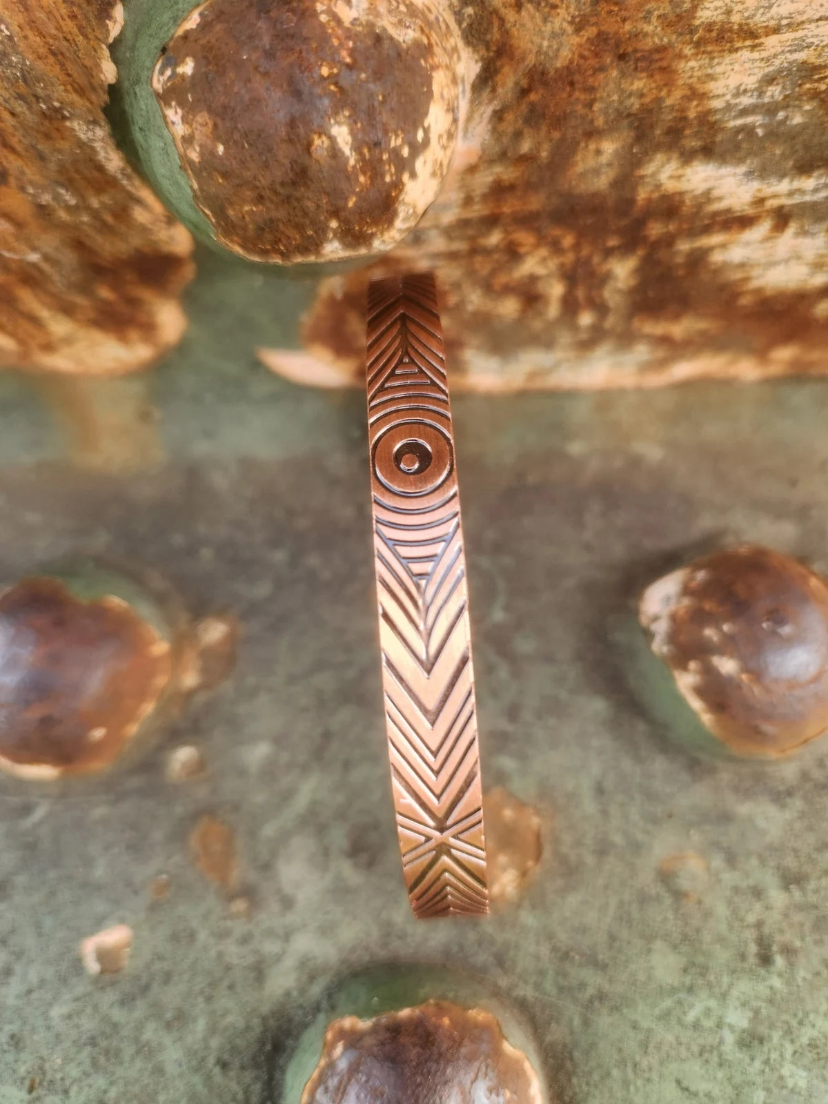 Detail of chevron and circle pattern on copper cuff