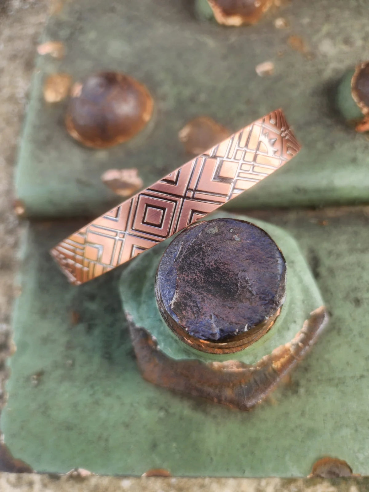 Diagonal view of diamond and cross motif on copper cuff bracelet