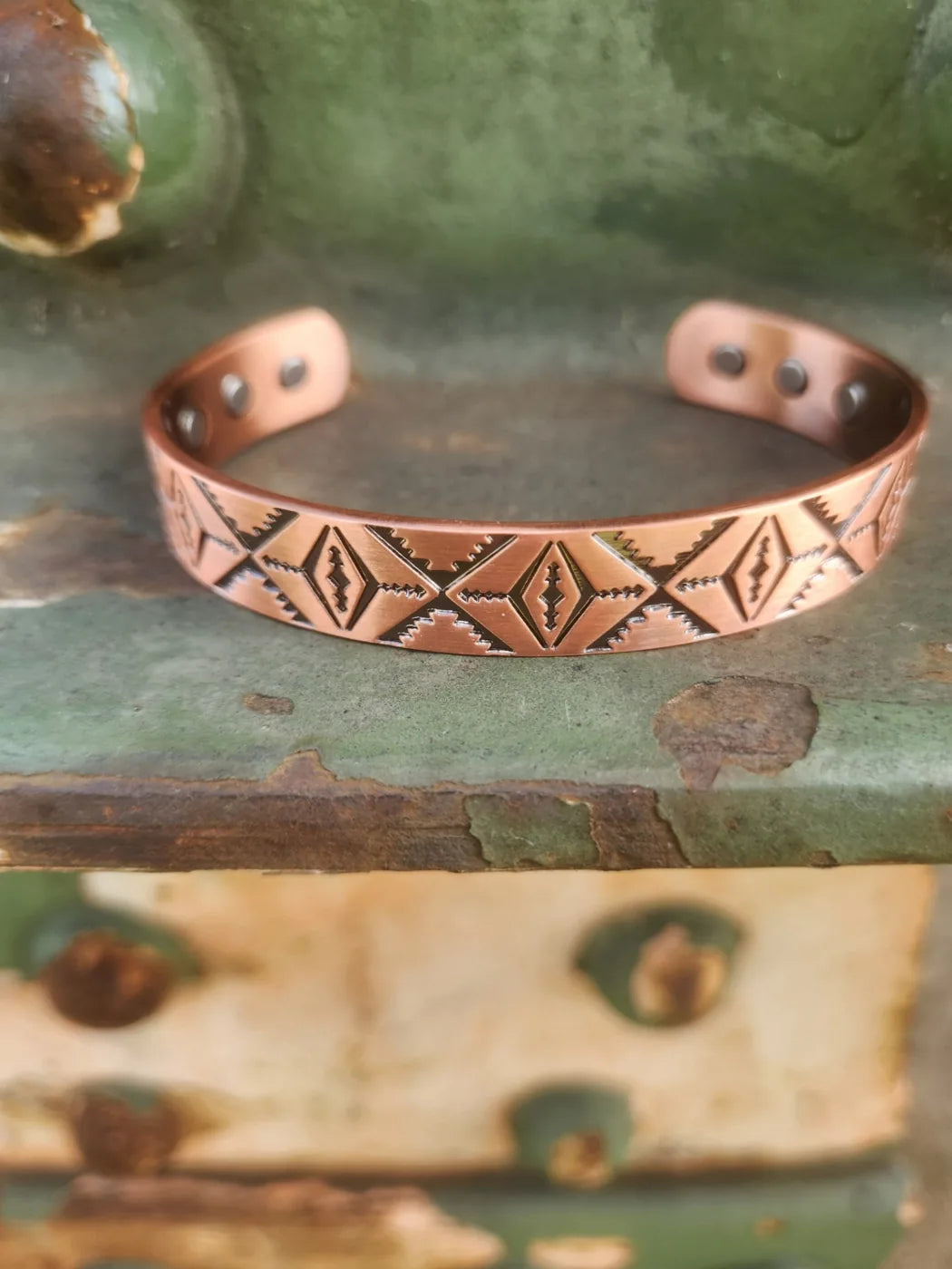 Front view of diamond and zigzag patterned copper cuff bracelet with inset magnets visible
