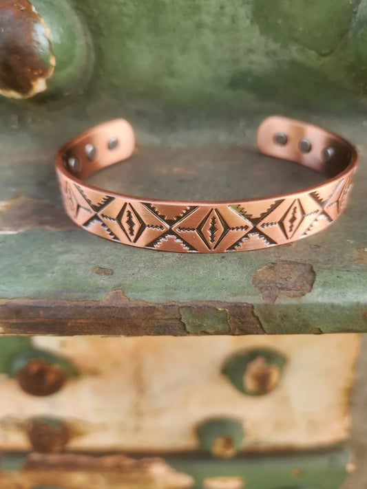 Front view of diamond and zigzag patterned copper cuff bracelet with inset magnets visible