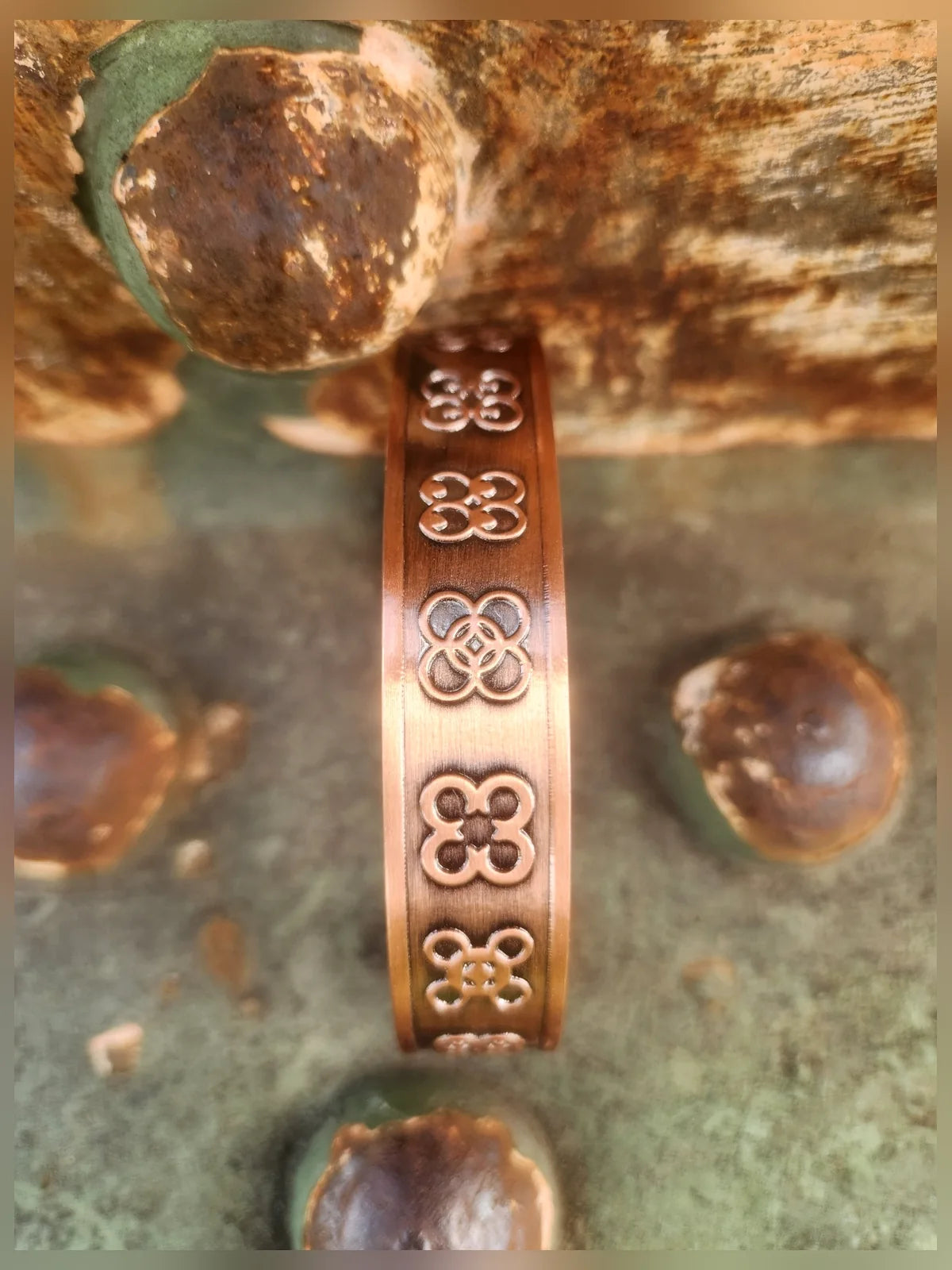 Close view of repeating four leaf motif on copper cuff