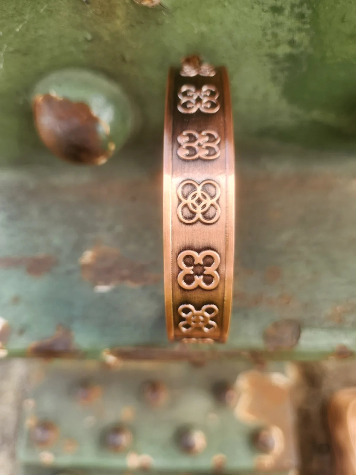 Side view of copper cuff bracelet featuring four leaf motif