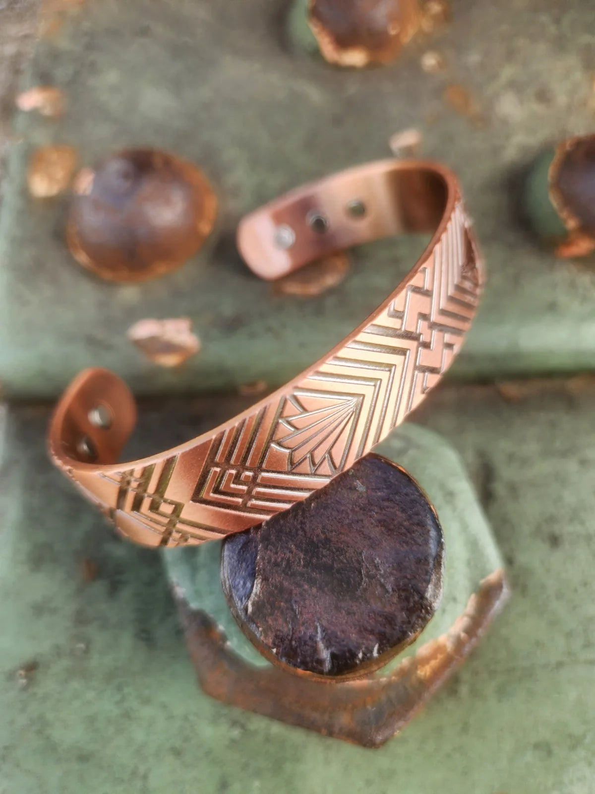 Angled view of copper cuff bracelet with bold geometric fan pattern and inset magnets
