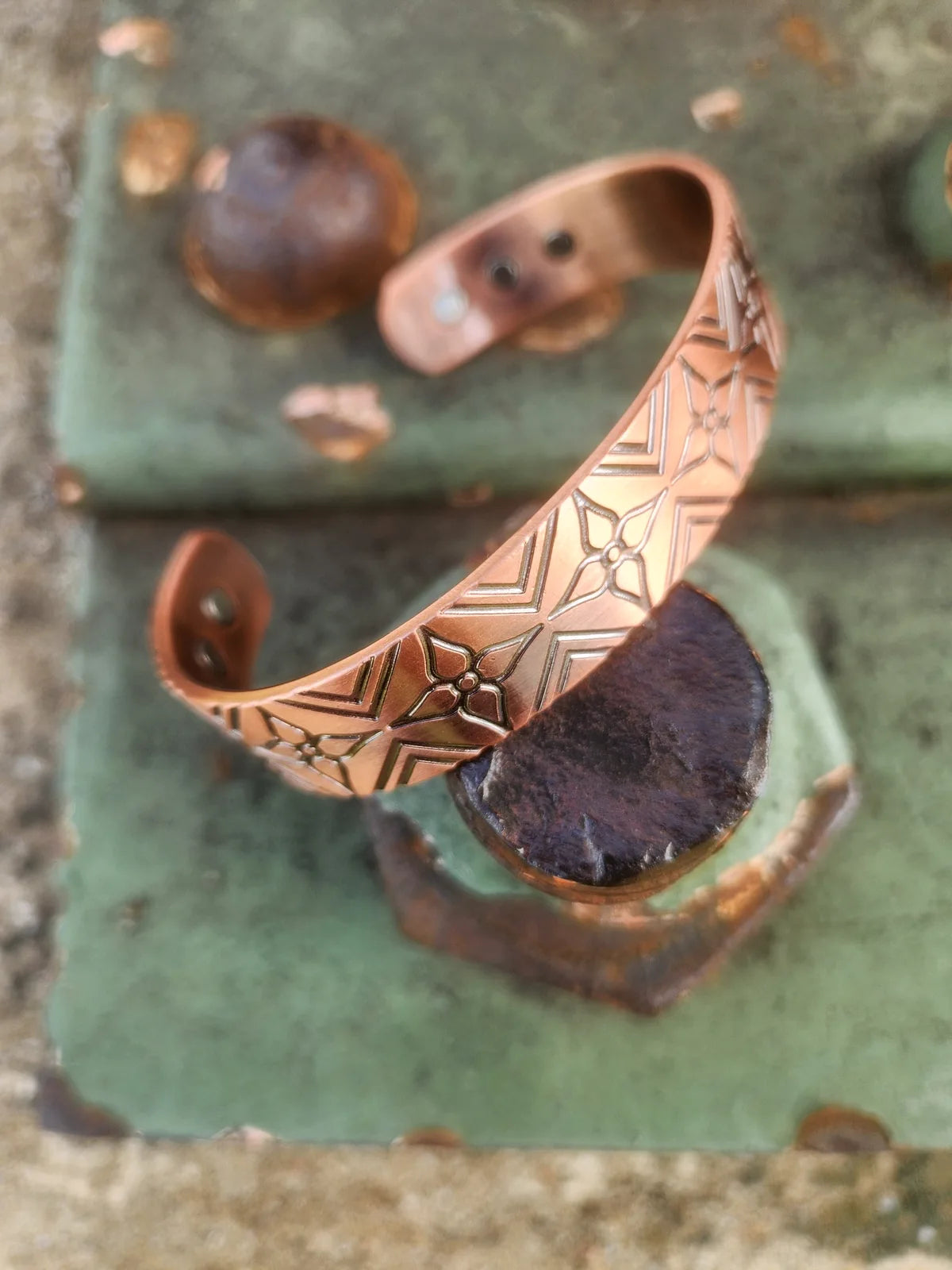 Magnetic copper cuff bracelet angled view showing engraved floral detail and embedded magnets
