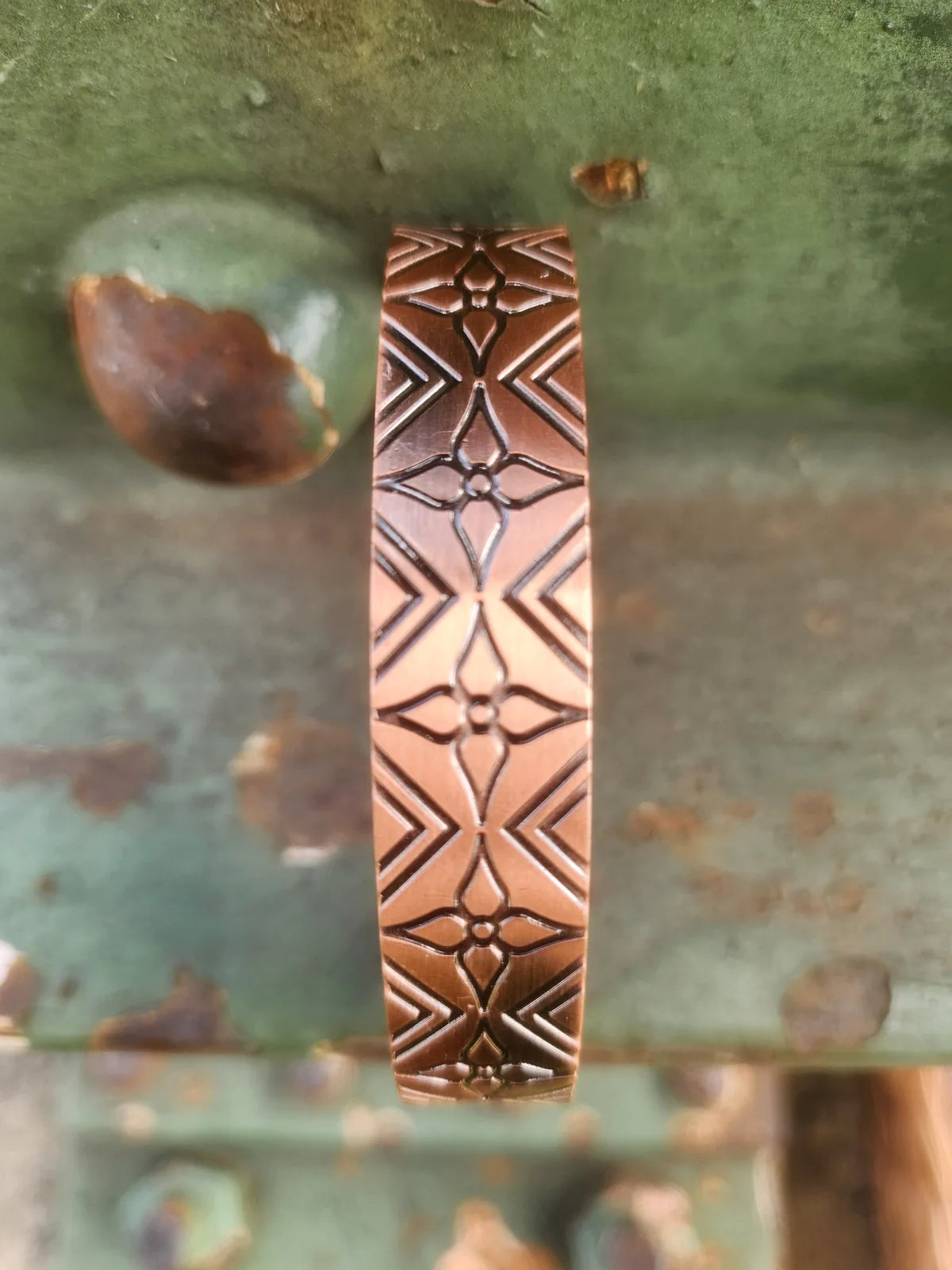 Detailed view of repeating geometric floral pattern on copper cuff bracelet