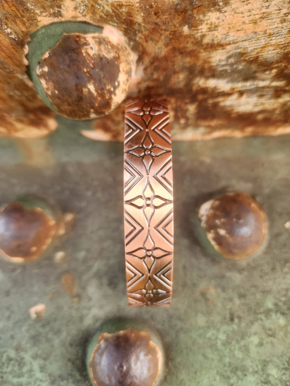 Close view of the geometric floral engraving on a copper magnetic cuff bracelet