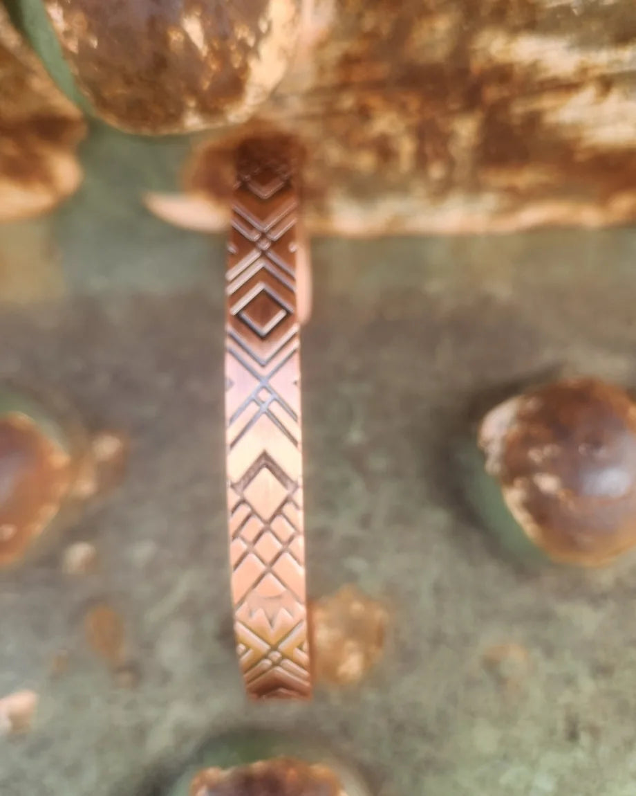 Close view of diamond and intersecting lines on narrow copper cuff