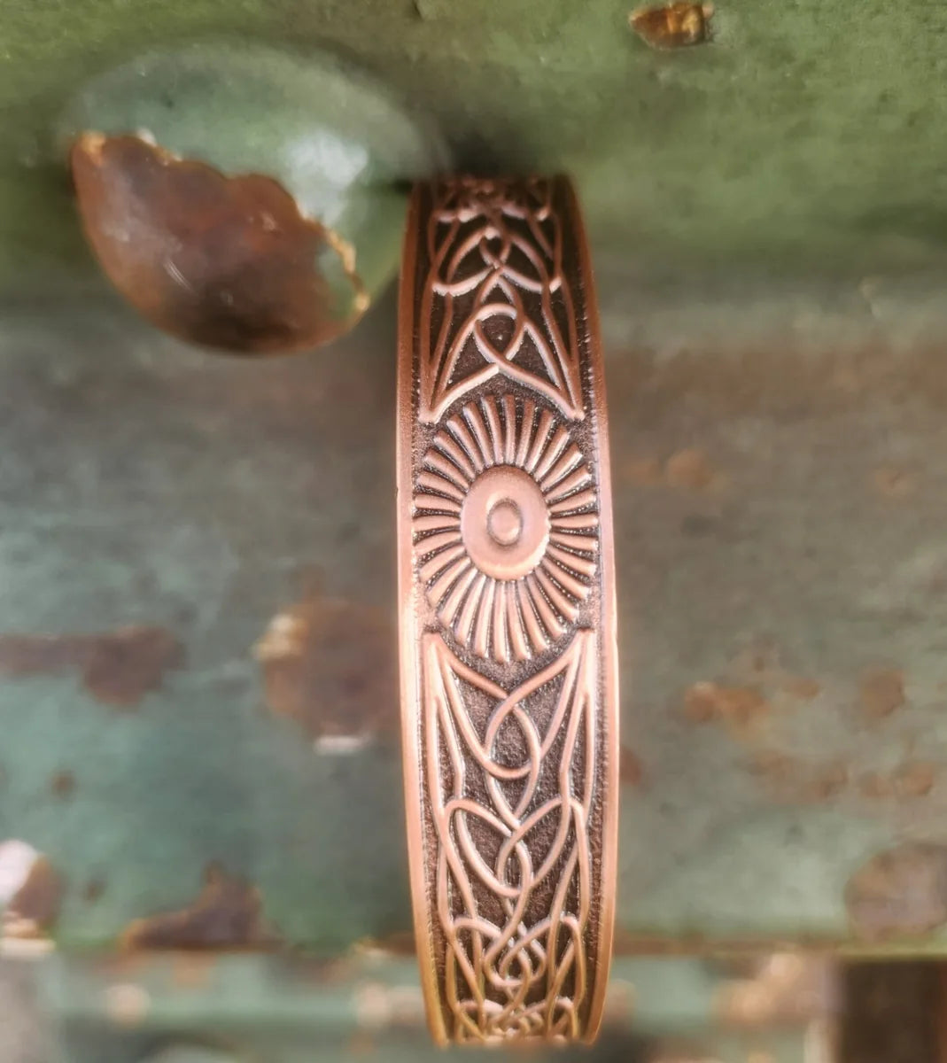 Close-up of interwoven knot motif on copper cuff