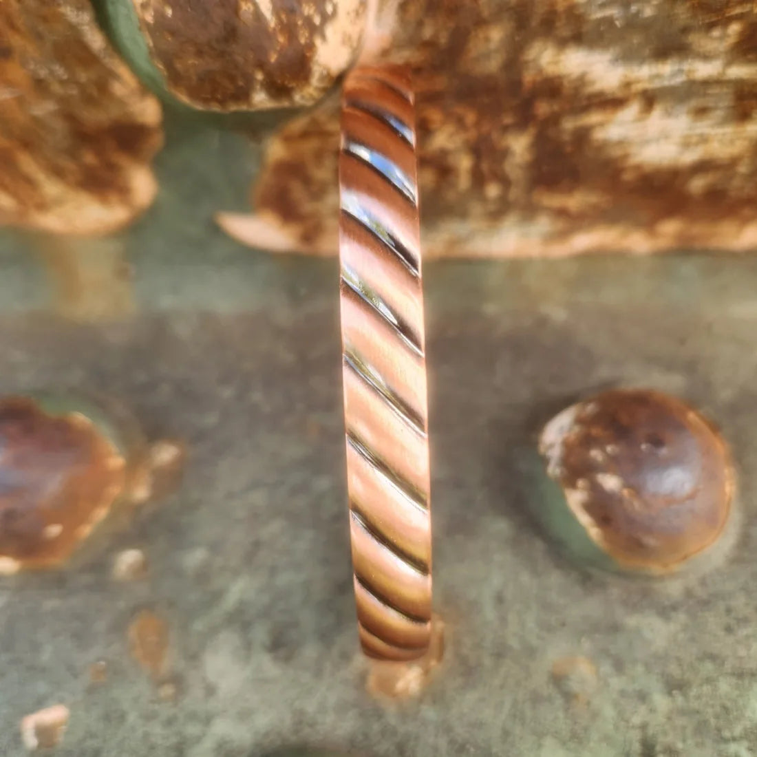 Vertical detail of diagonal twisted rope grooves on copper cuff